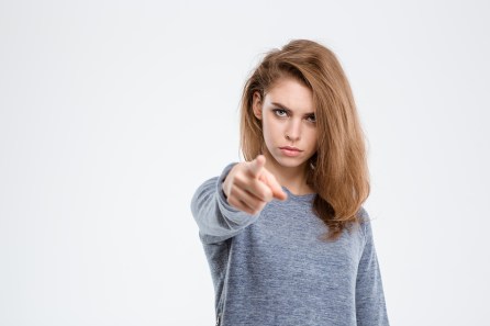 Portrait of angry woman pointing finger at camera isolated on a